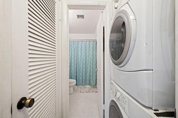 6531 SE Federal Hwy SE Unit Q108, Stuart, FL 34997 - clothes washing area with visible vents, tile patterned flooring, stacked washer and dryer, and laundry area
