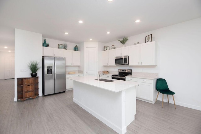 7568 NW Deysbrook Ln, Port Saint Lucie, FL 34987 - kitchen with white cabinets, a sink, light wood-style floors, stainless steel appliances, and light countertops