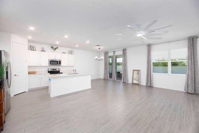 7568 NW Deysbrook Ln, Port Saint Lucie, FL 34987 - kitchen featuring light wood-style floors, stainless steel appliances, light countertops, open floor plan, and ceiling fan with notable chandelier