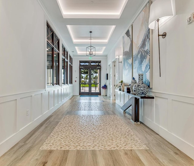 12408 Banner Ct, Palm Beach Gardens, FL 33412 - hallway featuring a raised ceiling, a decorative wall, wood finished floors, french doors, and a wainscoted wall