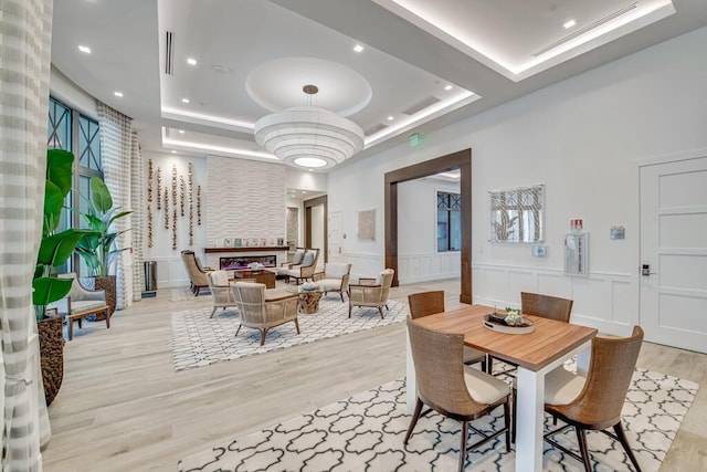 12408 Banner Ct, Palm Beach Gardens, FL 33412 - dining area featuring a tray ceiling, wood finished floors, a decorative wall, recessed lighting, and wainscoting