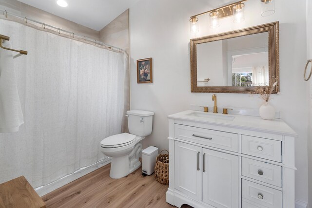 full bath featuring wood finished floors, curtained shower, vanity, and toilet