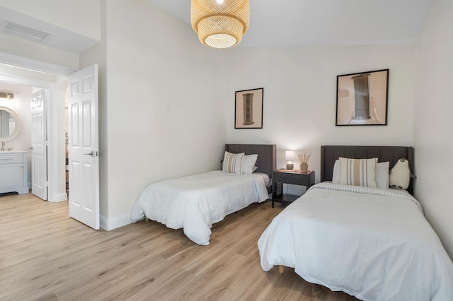 bedroom featuring light wood-style floors, lofted ceiling, visible vents, and baseboards