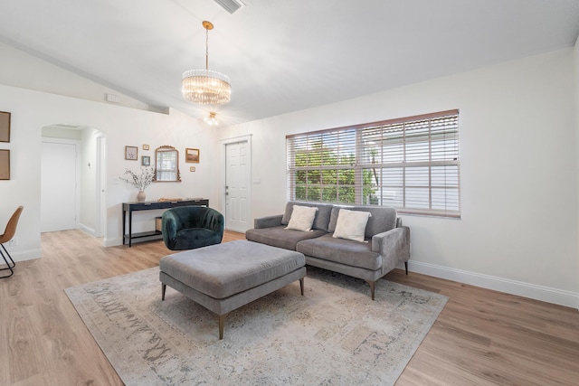 living area featuring arched walkways, vaulted ceiling, baseboards, a chandelier, and light wood-style floors