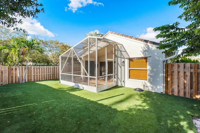 back of house with a yard, a tile roof, a fenced backyard, and stucco siding