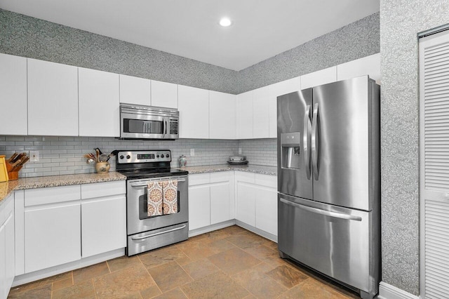 kitchen featuring white cabinets, stainless steel appliances, stone tile floors, and recessed lighting