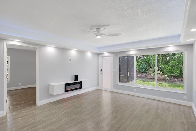 9305 Flynn Cir Unit 8, Boca Raton, FL 33496 - unfurnished living room with wood finished floors, ceiling fan, a glass covered fireplace, and a textured ceiling