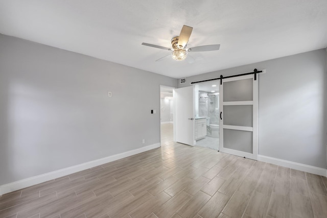 9305 Flynn Cir Unit 8, Boca Raton, FL 33496 - unfurnished room with a barn door, a ceiling fan, and light wood-style flooring