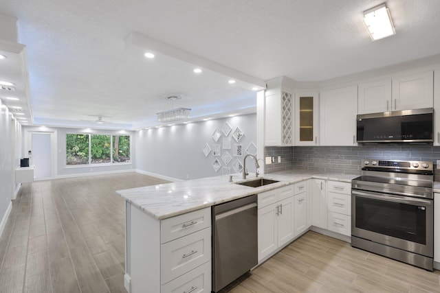 9305 Flynn Cir Unit 8, Boca Raton, FL 33496 - kitchen featuring appliances with stainless steel finishes, open floor plan, backsplash, a peninsula, and white cabinets