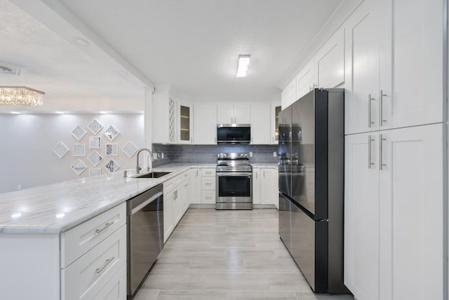 9305 Flynn Cir Unit 8, Boca Raton, FL 33496 - kitchen with stainless steel appliances, a peninsula, tasteful backsplash, white cabinets, and glass insert cabinets