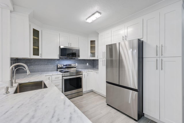 9305 Flynn Cir Unit 8, Boca Raton, FL 33496 - kitchen featuring appliances with stainless steel finishes, white cabinets, light stone countertops, and decorative backsplash