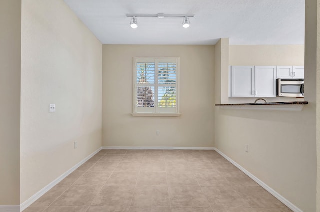 11039 Legacy Blvd Unit 203, Palm Beach Gardens, FL 33410 - unfurnished room with rail lighting, baseboards, and light tile patterned flooring