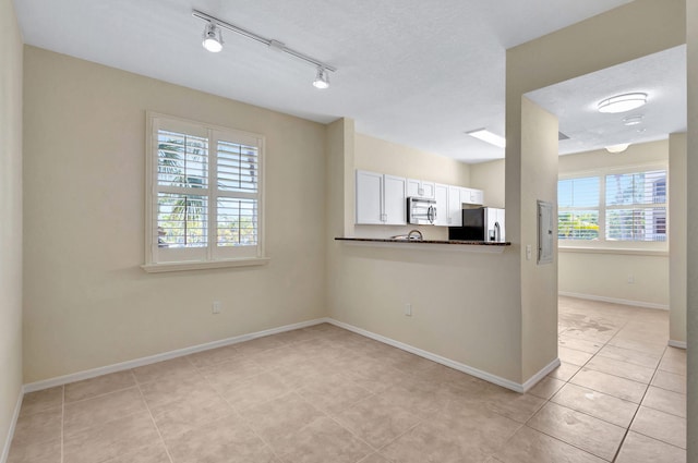 11039 Legacy Blvd Unit 203, Palm Beach Gardens, FL 33410 - interior space with rail lighting, baseboards, and light tile patterned floors