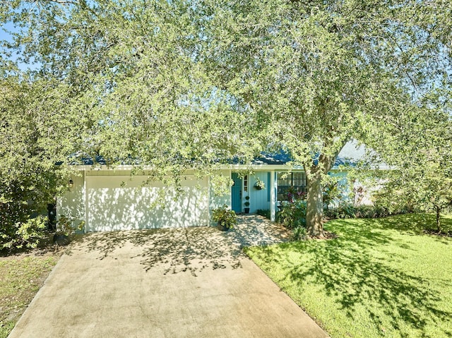 527 10th Ct, Vero Beach, FL 32962 - view of property hidden behind natural elements featuring a front lawn, concrete driveway, and a garage