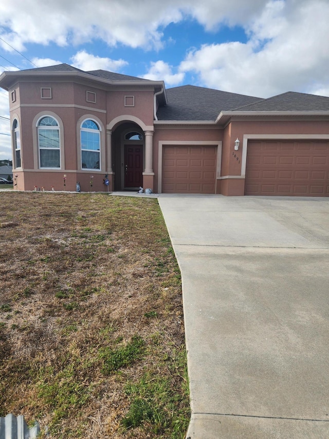 1691 SW Buttercup Ave, Port Saint Lucie, FL 34953 - view of front facade featuring an attached garage, a shingled roof, stucco siding, and concrete driveway