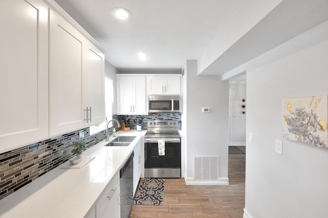 kitchen featuring a sink, visible vents, white cabinetry, backsplash, and appliances with stainless steel finishes