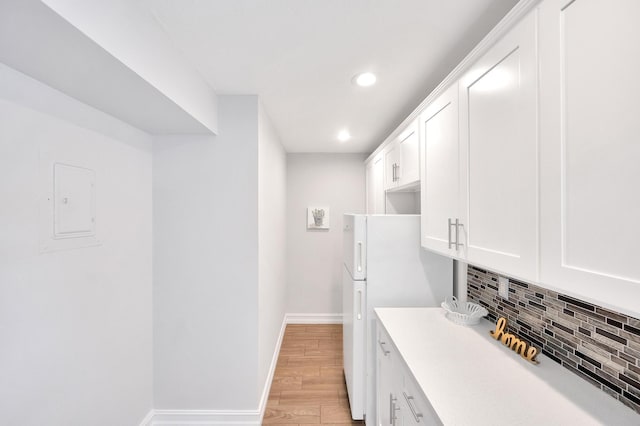kitchen with light wood finished floors, white cabinets, recessed lighting, backsplash, and light countertops