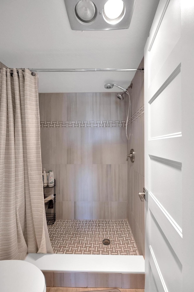 full bathroom featuring a tile shower and toilet