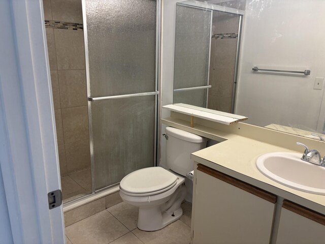 bathroom with toilet, vanity, tile patterned floors, and a stall shower