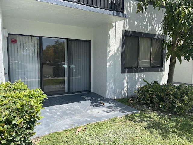 view of exterior entry with a patio area and stucco siding