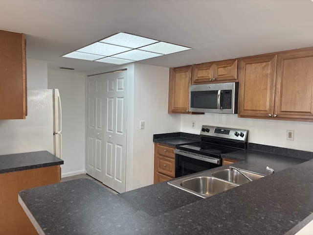 kitchen featuring brown cabinetry, appliances with stainless steel finishes, a sink, and visible vents