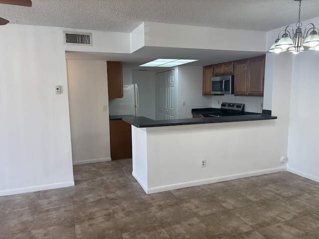 kitchen with dark countertops, appliances with stainless steel finishes, a textured ceiling, and visible vents