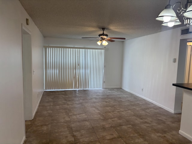 spare room featuring baseboards, a textured ceiling, visible vents, and ceiling fan with notable chandelier