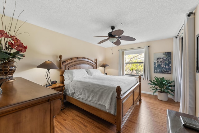 bedroom featuring a ceiling fan, a textured ceiling, and light wood-type flooring