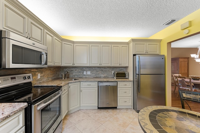 kitchen featuring a sink, a textured ceiling, visible vents, an inviting chandelier, and appliances with stainless steel finishes