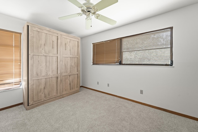 unfurnished bedroom with baseboards, a ceiling fan, and light colored carpet