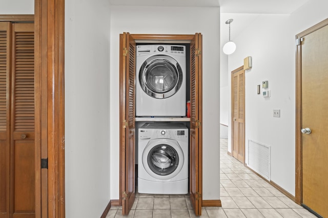 washroom with baseboards, stacked washer and dryer, laundry area, and light tile patterned floors