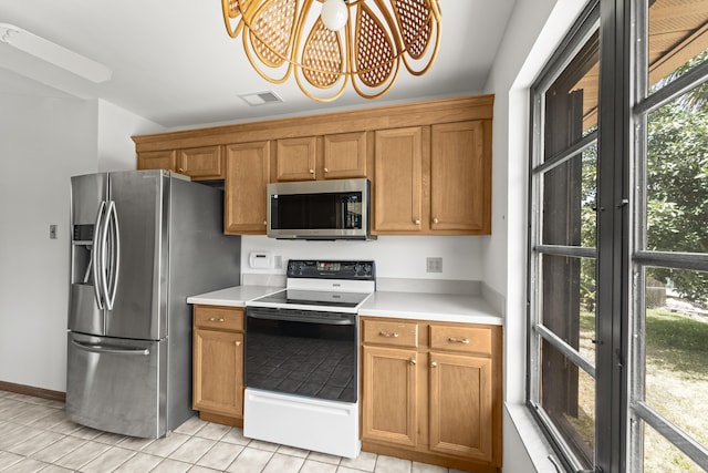 kitchen featuring light countertops, light tile patterned floors, stainless steel appliances, and a chandelier