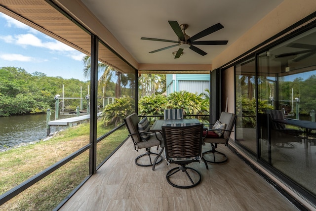 sunroom with a ceiling fan, a water view, and a healthy amount of sunlight