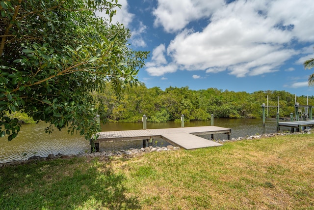 view of dock with a lawn and a water view