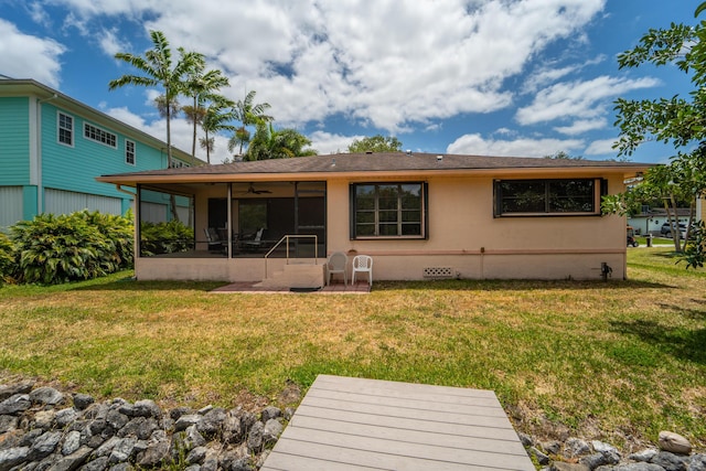 back of property featuring a ceiling fan, a lawn, a sunroom, a patio, and stucco siding