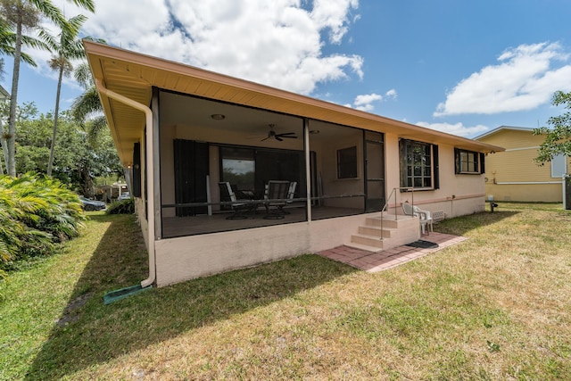 rear view of property featuring a sunroom, a ceiling fan, and a yard
