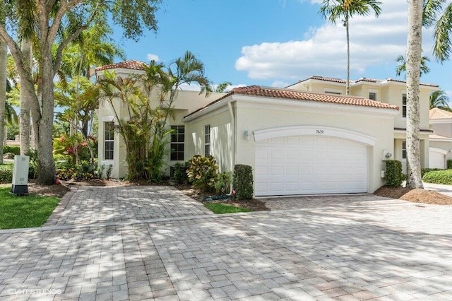 mediterranean / spanish-style home featuring decorative driveway, a garage, stucco siding, and a tile roof