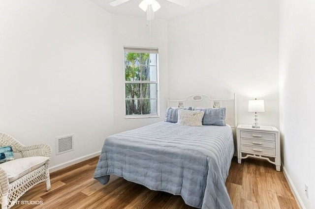 bedroom featuring a ceiling fan, baseboards, visible vents, and wood finished floors