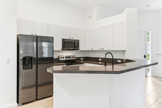 kitchen featuring stainless steel appliances, white cabinetry, a sink, and a peninsula