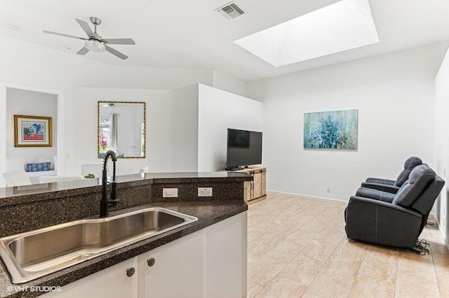 kitchen with visible vents, dark countertops, open floor plan, a sink, and a skylight