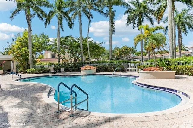 community pool with a patio area and fence