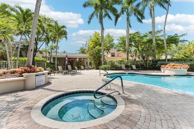 community pool with fence, a community hot tub, and a patio area