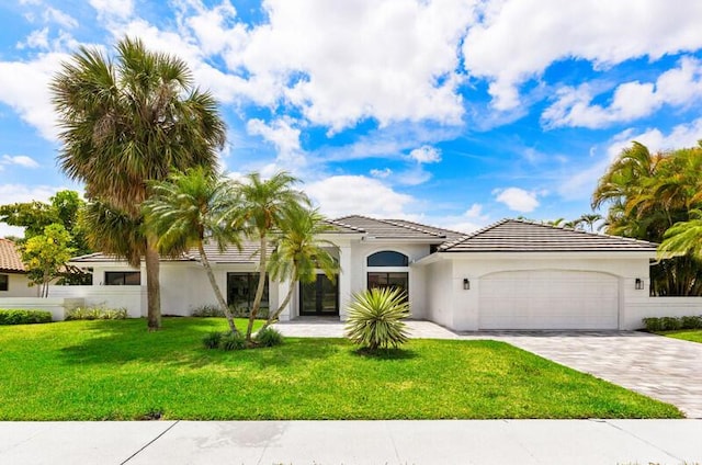 11020 Boca Woods Ln, Boca Raton, FL 33428 - mediterranean / spanish home featuring an attached garage, decorative driveway, a front lawn, stucco siding, and a tiled roof