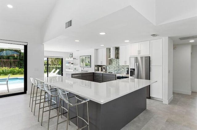 11020 Boca Woods Ln, Boca Raton, FL 33428 - kitchen with wall chimney range hood, light countertops, a kitchen breakfast bar, stainless steel appliances, and white cabinetry