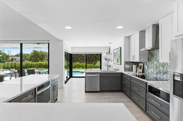 11020 Boca Woods Ln, Boca Raton, FL 33428 - kitchen with wall chimney range hood, appliances with stainless steel finishes, light countertops, white cabinets, and tasteful backsplash