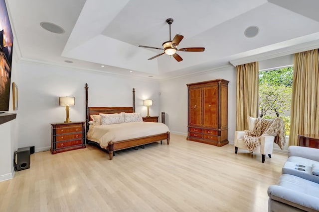 bedroom with a raised ceiling, light wood finished floors, baseboards, a ceiling fan, and crown molding
