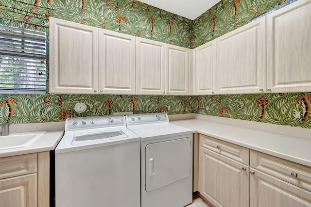 clothes washing area with wallpapered walls, cabinet space, and washing machine and clothes dryer