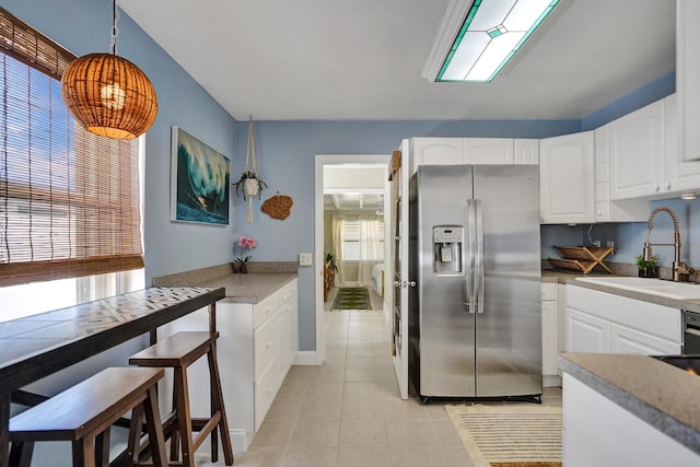 1008 SE 3rd St, Boynton Beach, FL 33435 - kitchen with a sink, hanging light fixtures, light tile patterned flooring, stainless steel refrigerator with ice dispenser, and white cabinetry