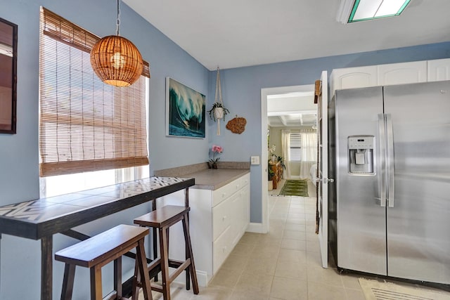 1008 SE 3rd St, Boynton Beach, FL 33435 - kitchen with light tile patterned floors, pendant lighting, baseboards, white cabinetry, and stainless steel refrigerator with ice dispenser