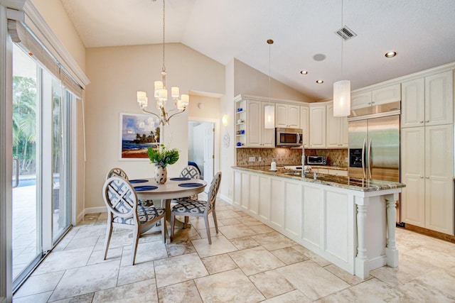 kitchen featuring stainless steel appliances, vaulted ceiling, stone counters, decorative backsplash, and a peninsula
